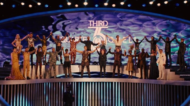 The 75th Hunger Games' tributes hold hands atop a stage