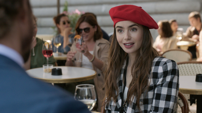Emily wearing a red beret at a cafe on Emily in Paris