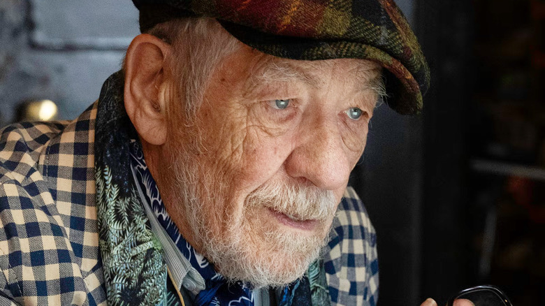 Ian McKellen as Julian Sklar wearing a beret and looking at a laptop in The Christophers