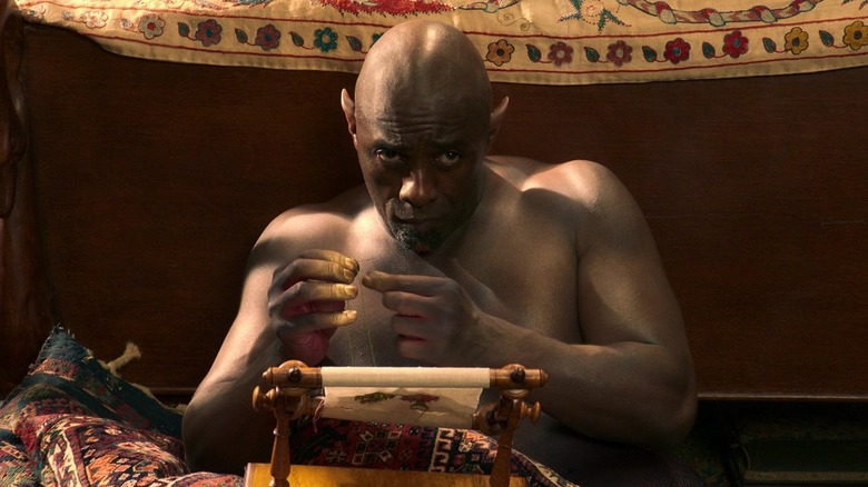 The Djinn looking shy while reading from a parchment in Three Thousand Years of Longing