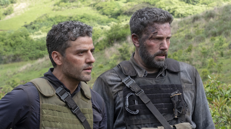 Oscar Isaac dans le rôle de Santiago debout à côté de Ben Affleck dans le rôle de Tom sur les terres du fermier dans Triple Frontier