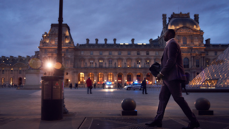 Assane walking outside of the Louvre in Lupin