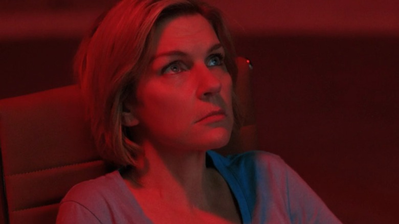 Pluribus - Close-up of Carol, bathed in red light, looking pensive