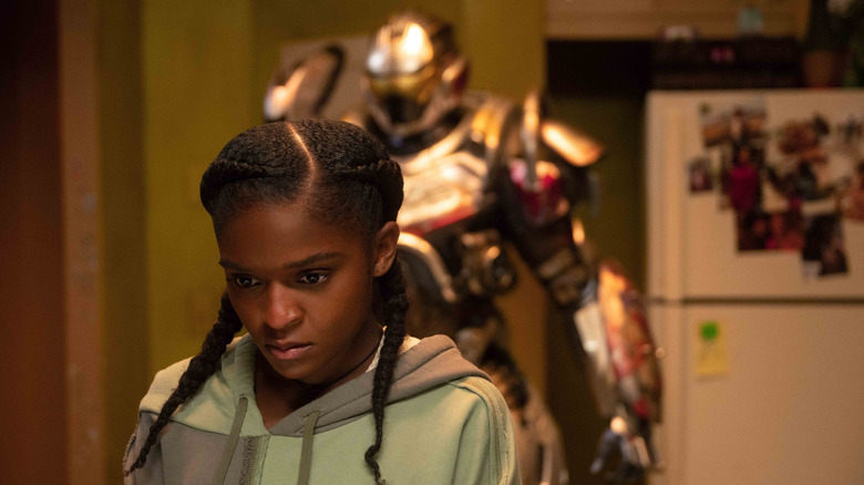 Dominique Thorne as Riri Williams standing in front of her armor in her kitchen in Ironheart