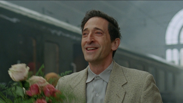 László Tóth carrying flowers in The Brutalist