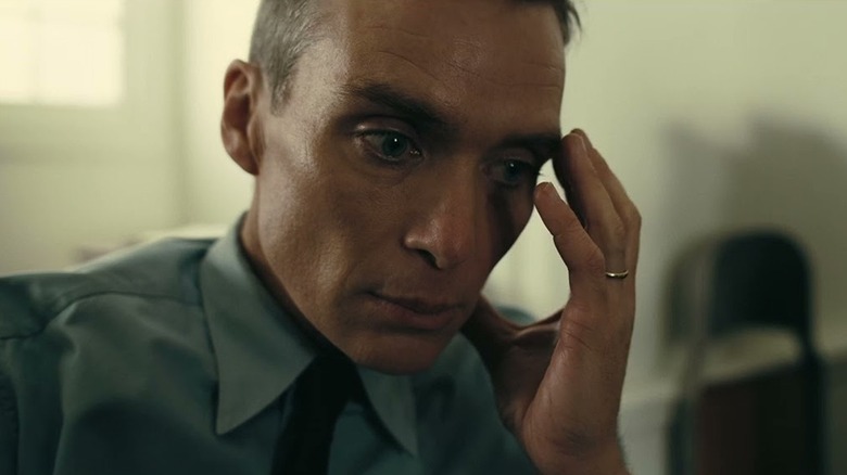 Cillian Murphy as J Robert Oppenheime with his palm to his face in Oppenheimer