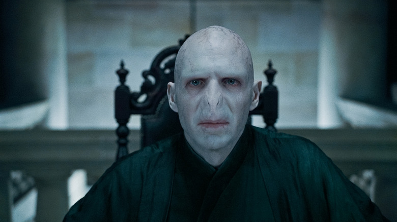 Ralph Fiennes as Voldemort sitting at a table in Harry Potter and the Deathly Hallows: Part 1