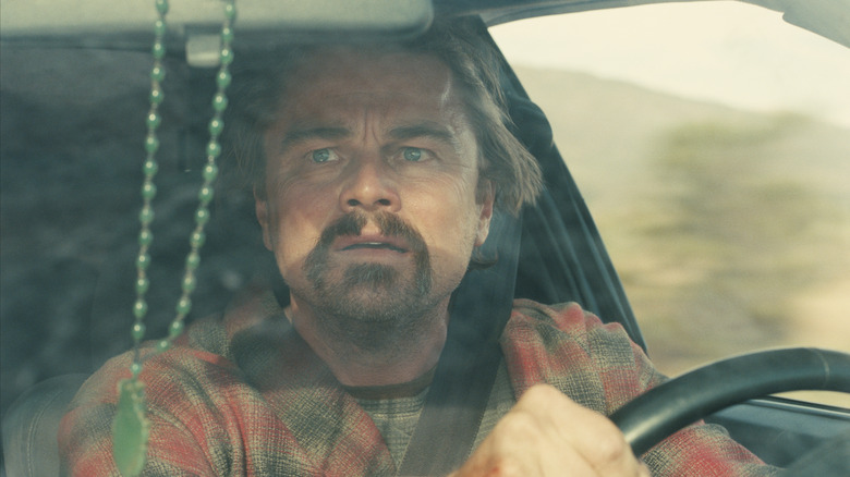 Bob looking in horror and fear as he drives down a long road in One Battle After Another