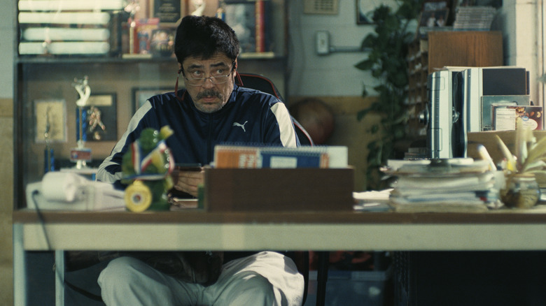 Sensei Sergio St. Carlos lowering his glasses from his desk in One Battle After Another