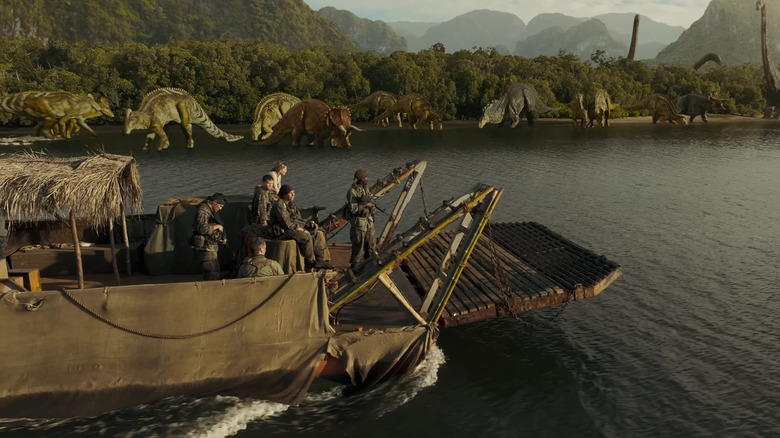 The team on the boat looks at many dinosaurs on the beach in the primitive war