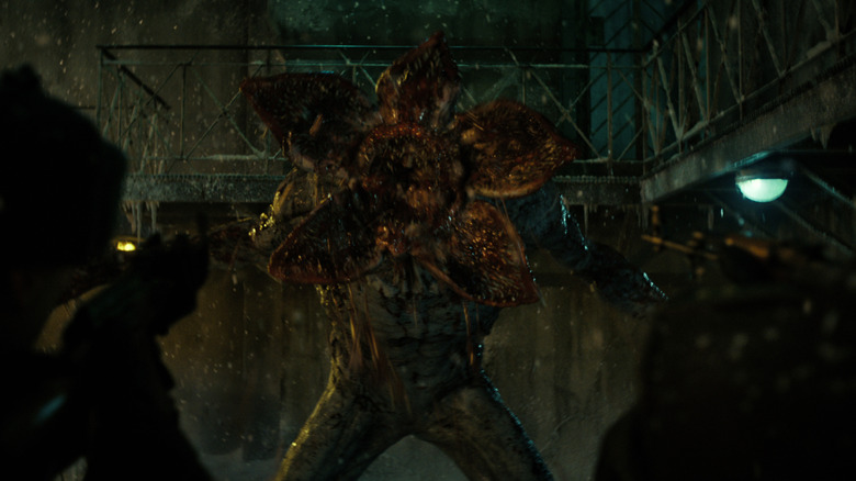 Soldiers aiming guns at a Demogorgon that's roaring in Stranger Things