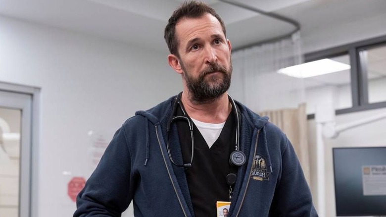 Dr. Robby looking at something concerned in scrubs and a hoodie on The Pitt