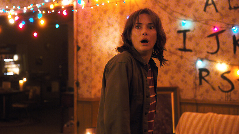Winona Ryder as Joyce with a look of shock on her face in her living room in Stranger Things season 1