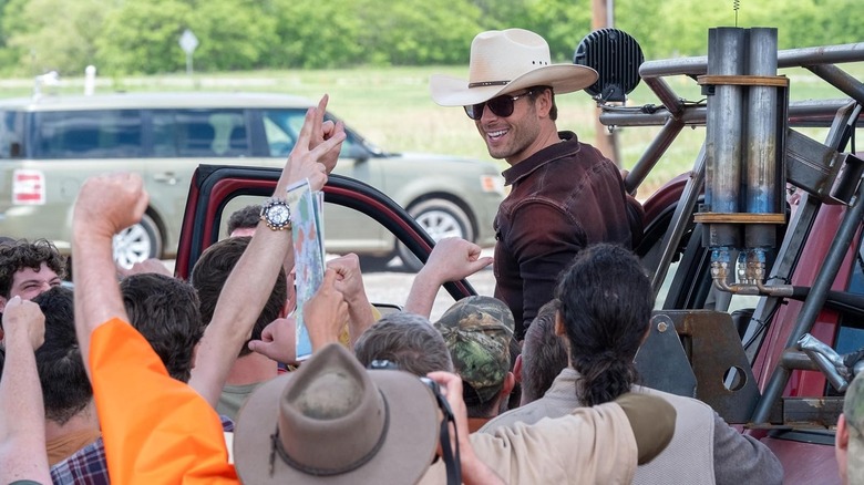 Tyler Owens grinning in his cowboy hat, surrounded by people, in Twisters