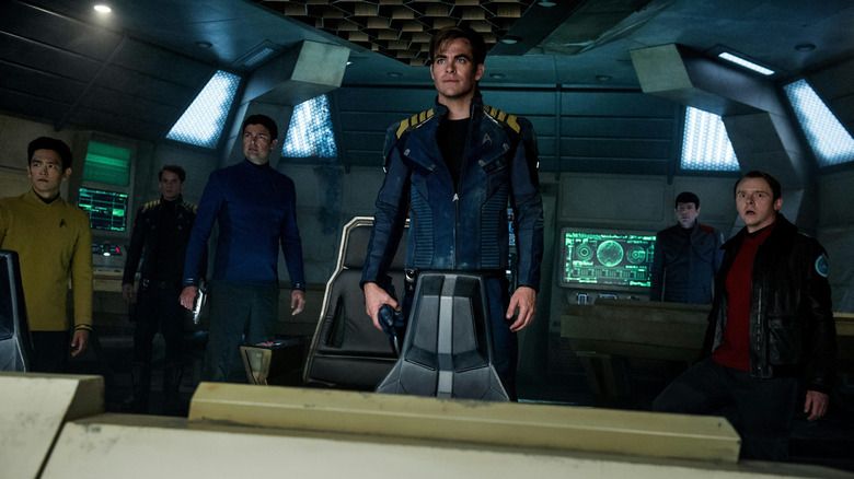 John Cho as Hikaru Sulu, Anton Yelchin as Pavel Chekov, Karl Urban as Leonard McCoy, Chris Pine as James Kirk, Zachary Quinto as Spock, and Simon Pegg as Montgomery Scott standing on the bridge of a starship in Star Trek Beyond
