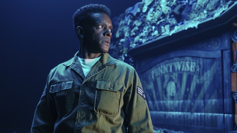 Chris Chalk as Dick Hallorann standing in front of a Pennywise the Clown inscription in It: Welcome to Derry