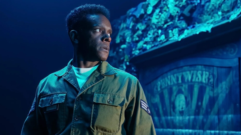 Dick stands in front of Pennywise's trailer in It: Welcome to Derry