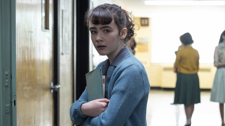 Clara Stack as Lily holding books in school in It: Welcome to Derry episode 1