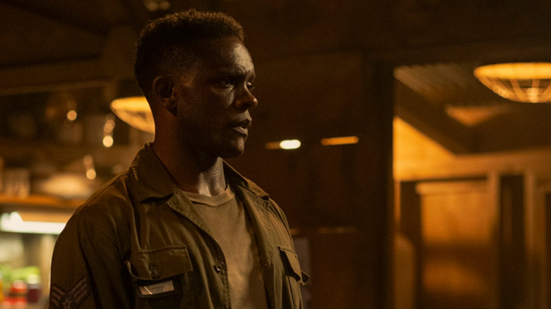 Chris Chalk's Dick Hallorann stands in a dimly lit room in It Welcome to Derry