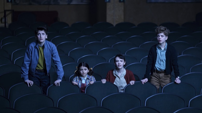Clara Stack as Lilly, Mikkal Karim-Fidler as Teddy, Jack Molloy Legault as Phil, and Hunter Storm Baker as Suze looking horrified in a movie theater on It: Welcome to Derry