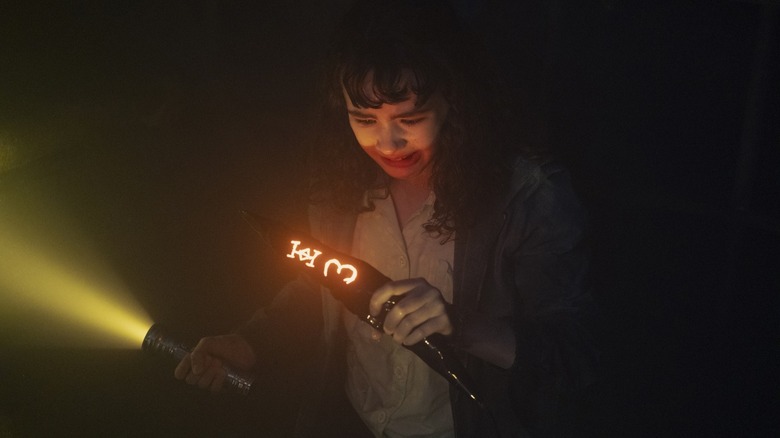 Clara Stack's Lilly Bainbridge looks down as she holds a pillar in It Welcome to Derry