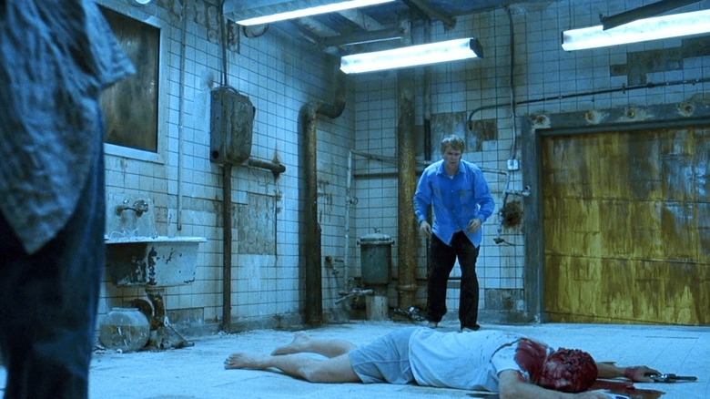 Lawrence looks at a corpse in the torture bath in Saw