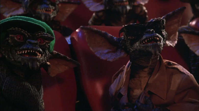 கிரெம்லின்ஸில் உள்ள ஒரு திரையரங்கில் பச்சை நிற தொப்பியில் ஒரு கிரெம்லின் மற்றும் சன்கிளாஸில் ஒரு கிரெம்லின்