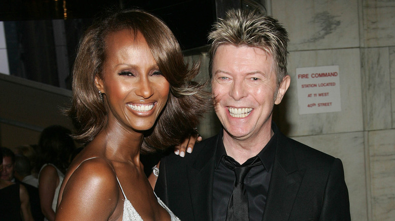 a woman smiling next to a smiling man in a black suit
