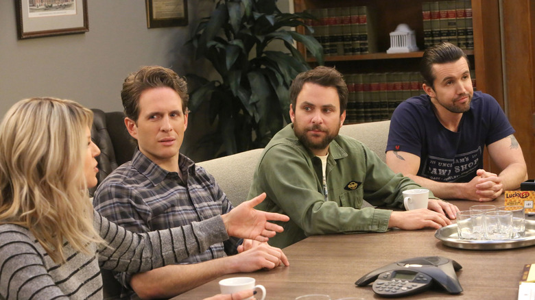 Kaitlin Olson as Dee, Glenn Howerton as Dennis, Charlie Day as Charlie, and Rob McElhelley as Mac sitting around a table on It's Always Sunny in Philadelphia