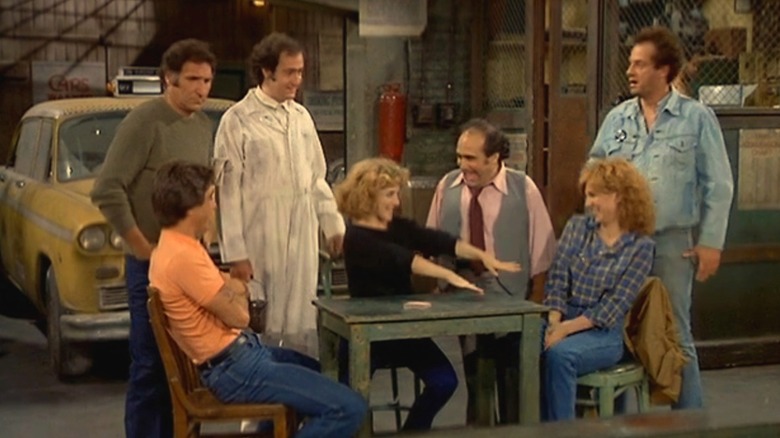 The cast of Taxi gathered around the garage with Simka in the middle, showing off her ring