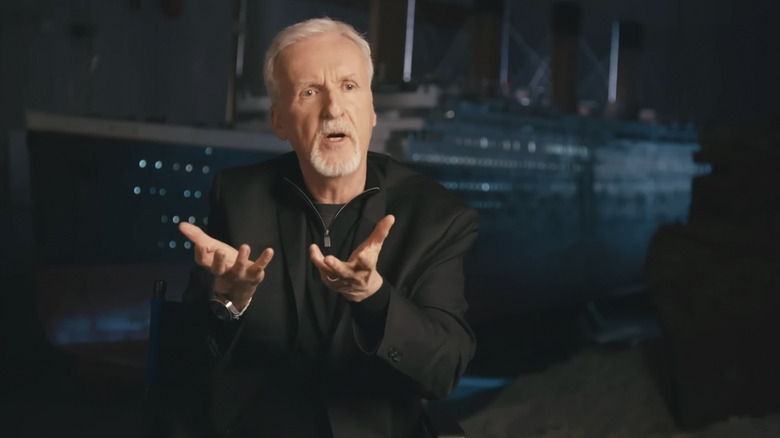 James Cameron in a behind the scenes video with a fake Titanic ship behind him
