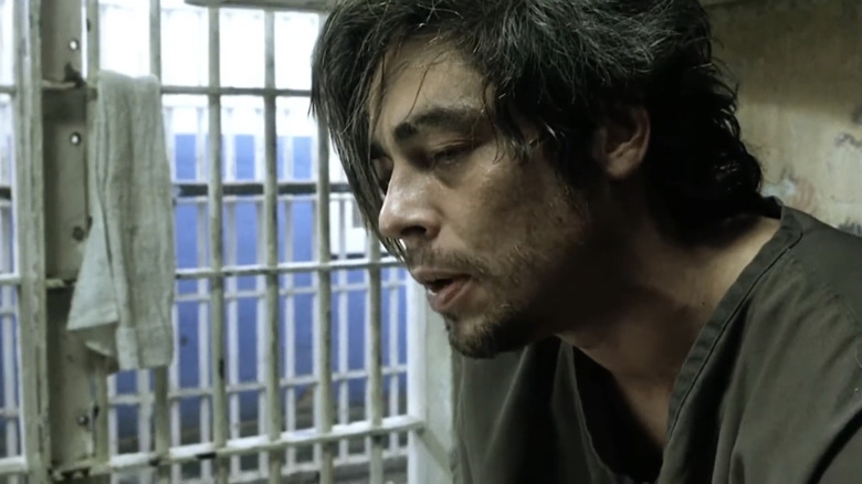 బెనిసియో డెల్ టోరో యొక్క జాక్ జోర్డాన్ 21 గ్రాముల జైలు గదిలో కూర్చున్నప్పుడు నిరుత్సాహంగా కనిపిస్తున్నాడు