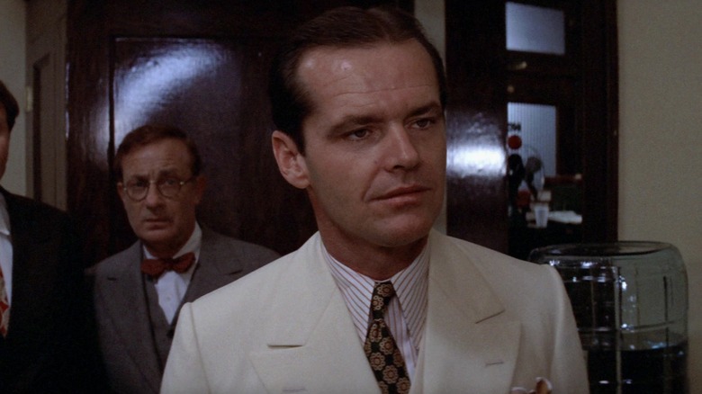 Jake Gittes in a white suit with a guy in glasses behind him in Chinatown
