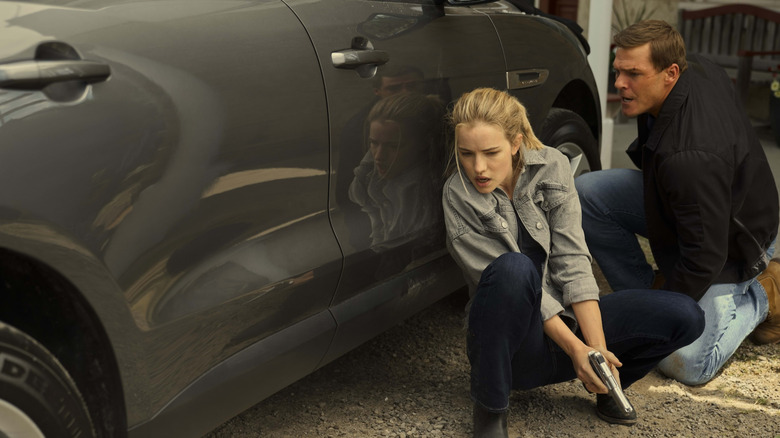 Roscoe and Jack Reacher kneeling next to a car in Reacher