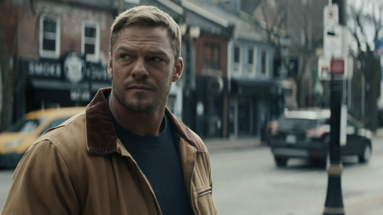 Alan Ritchson enquanto Jack Reacher fica na rua em Reacher