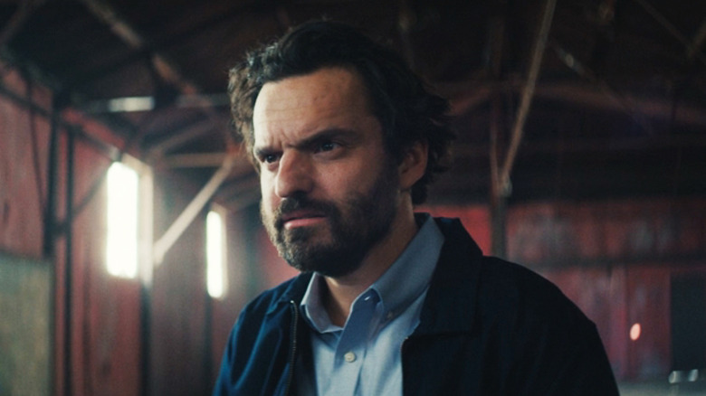 Jake Johnson's Tommy is seen in closeup as he stands in a hanger in Self Reliance