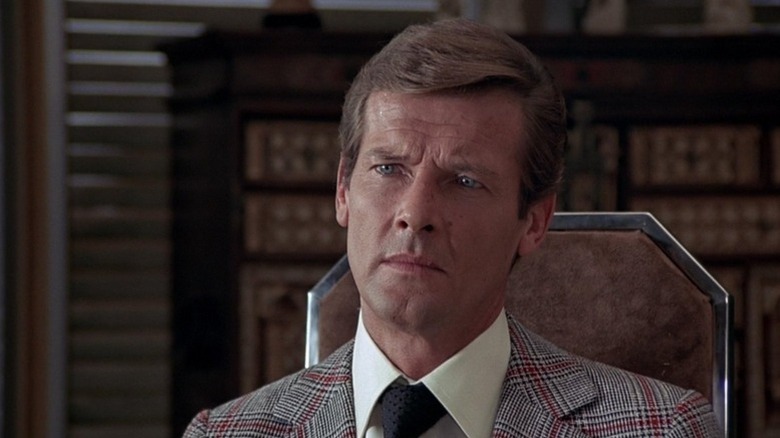 Roger Moore's James Bond sitting in a chair in The Man With the Golden Gun