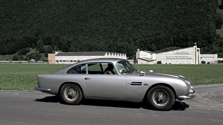 The 1964 Aston Martin DB5 on a street next to an Auric Enterprises plant in Goldfinger