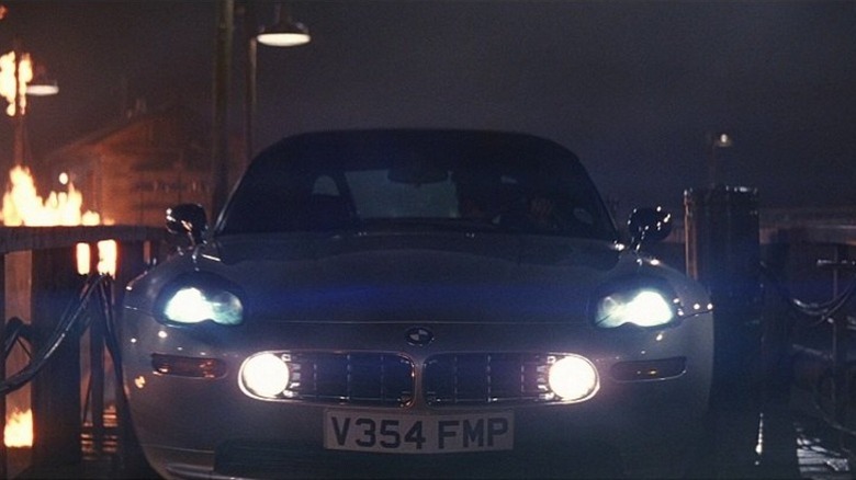 The 1999 BMW Z8 with headlights on atop a wood bridge near a fire at night in The World Is Not Enough