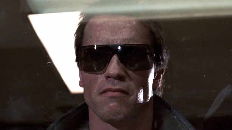 The T-800 looking through a glass panel while wearing sunglasses in The Terminator