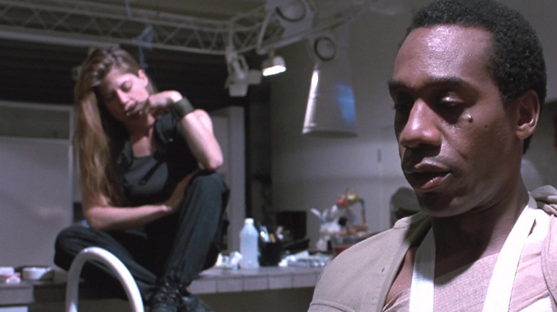 Linda Hamilton's Sarah Connor sits on a kitchen cabinet while Joe Morton's Miles Dyson looks dejected in the foreground in Terminator 2 Judgment Day