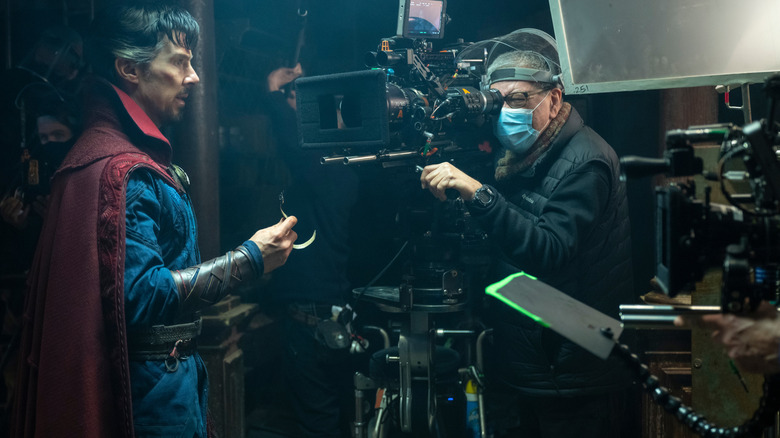 Benedict Cumberbatch as Stephen Strange filming a scene in front of a camera operator in a behind-the-scenes still from Doctor Strange in the Multiverse of Madness