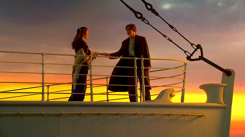 Kate Winslet and Leonardo DiCaprio stand aboard the ship deck at sunset in Titanic