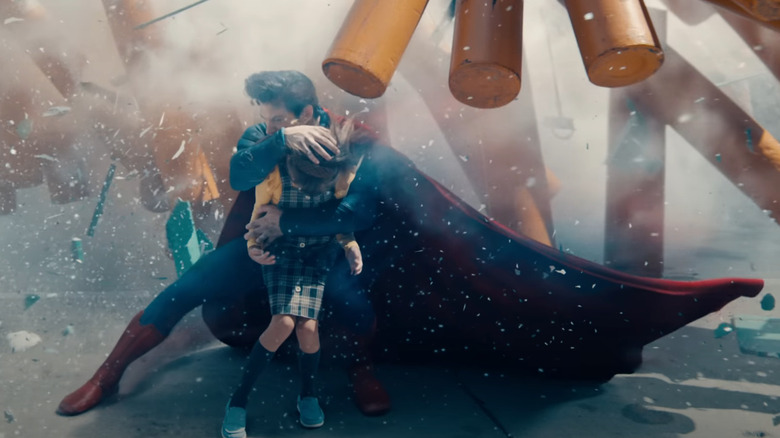 David Corenswet as Superman protecting a child from exploding debris in Superman (2025)