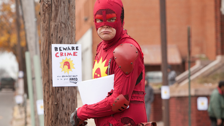 The Crimson Bolt putting a sign on a telephone pole in the movie Super