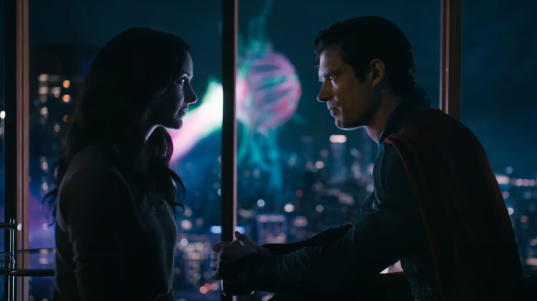 Superman and Lois Lane talking in an apartment at night while the Justice Gang fights a monster in the background in Superman