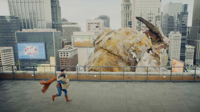 David Corenswet's Superman holds a woman as he lands on a roof with a Zesti Cola billboard visible in the background in Superman