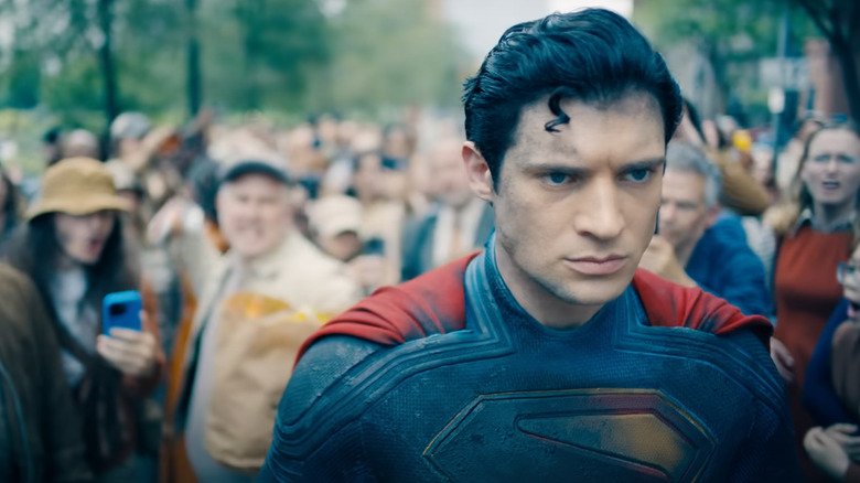 David Corenswet as Superman walking solemnly through an angry crowd in Superman