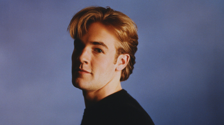 James Van Der Beek circa the Dawson's Creek era in a black shirt on a blue background