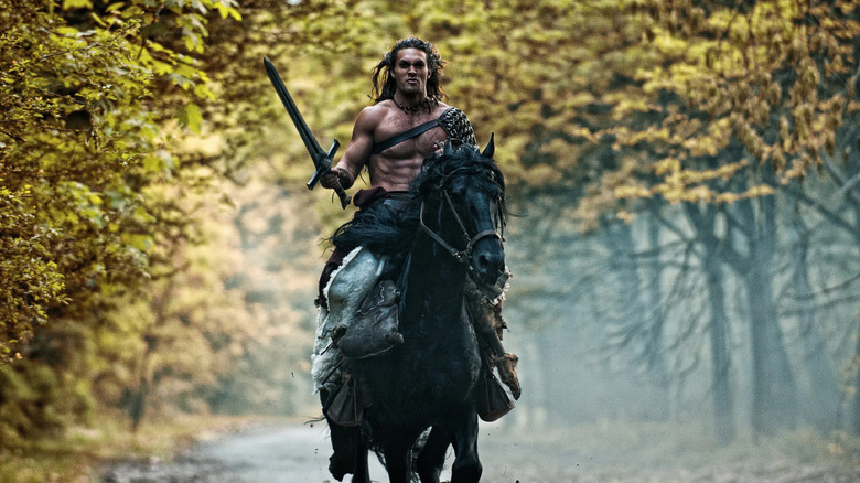 Jason Momoa as Conan riding on his horse holding his sword in Conan the Barbarian (2011)
